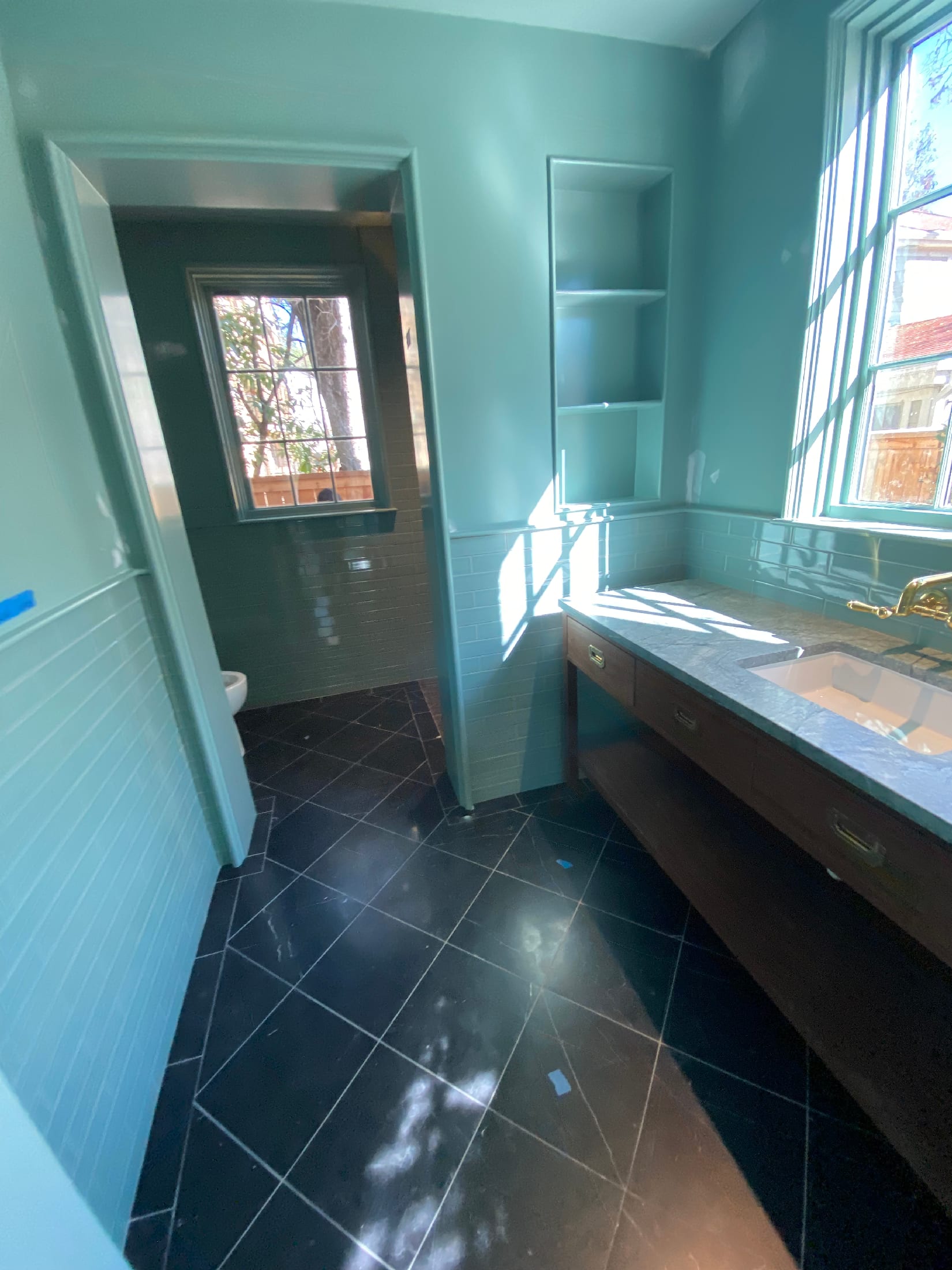 Bathroom with a walnut vanity, marble counter, blue subway wainscot, and a dark slate floor.