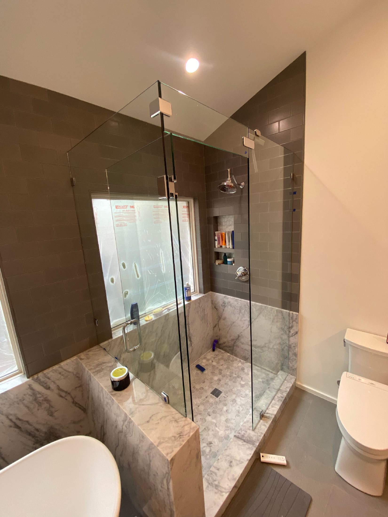 Walk-in shower with gray subway tile walls, a Carrara marble half-wall, and a hex marble shower floor.