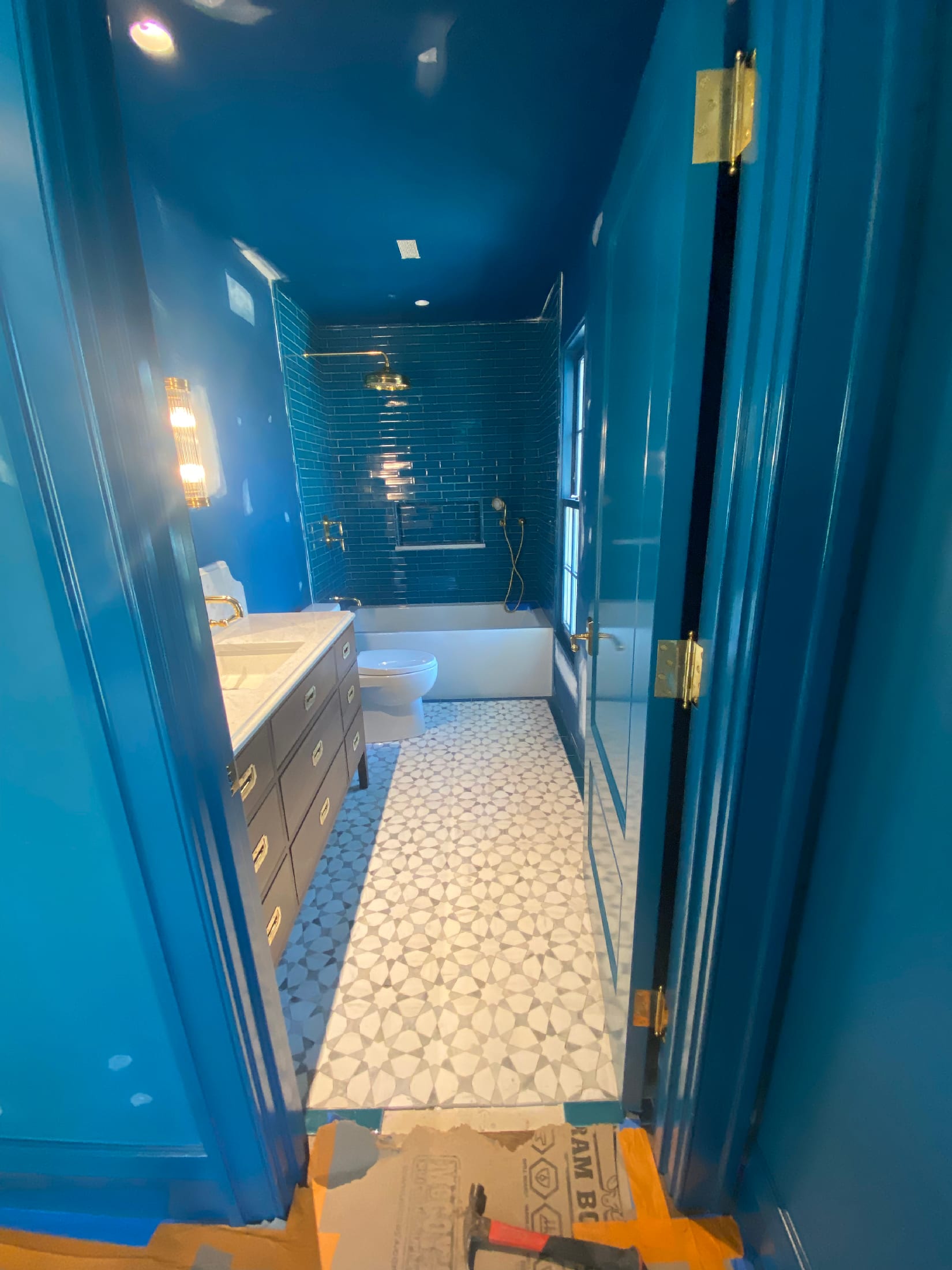 Saturated cobalt bath with dark blue subway shower walls and a Moroccan-style mosaic tile floor.