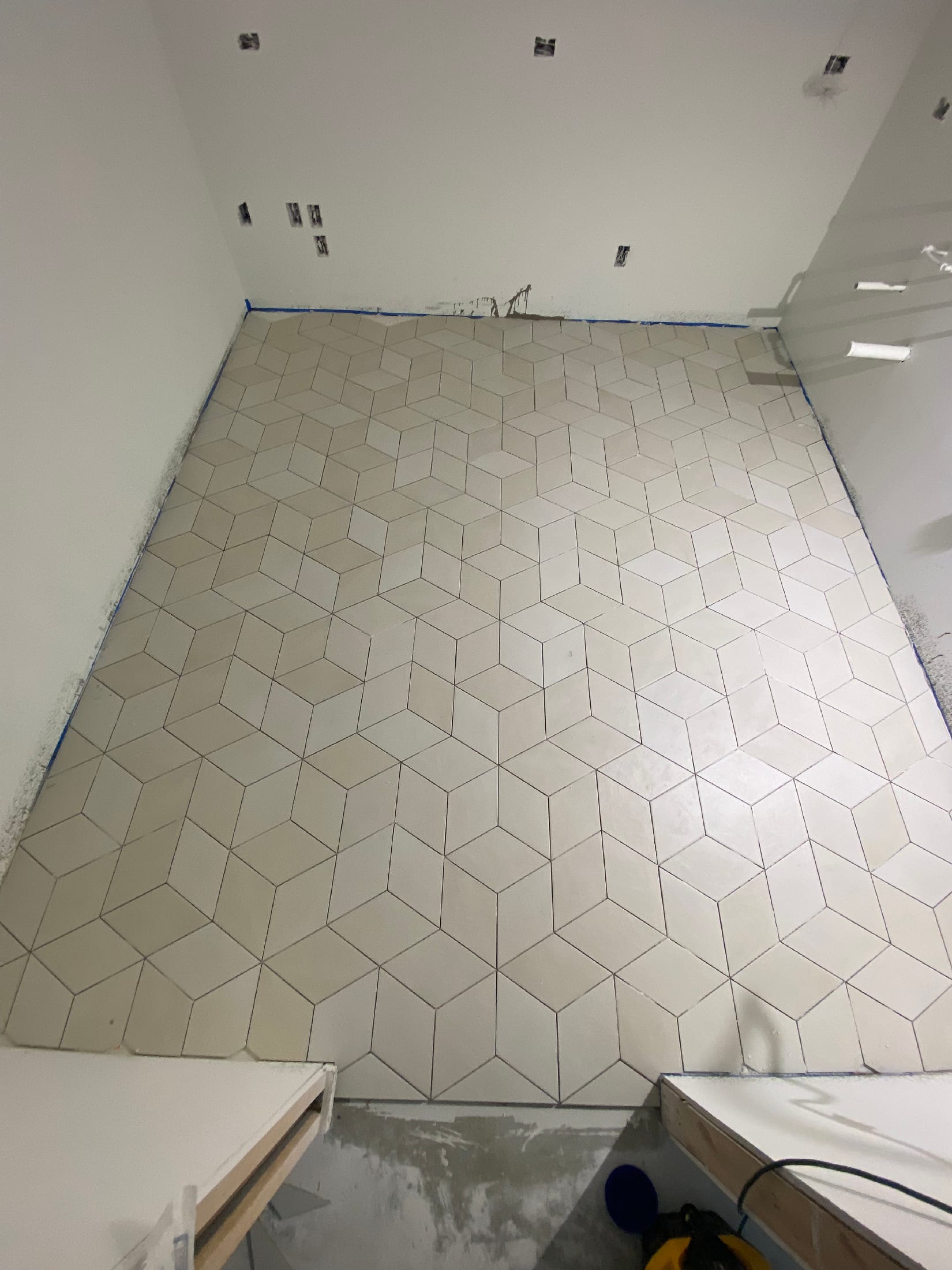 Floor in cream rhombus tile arranged in a tessellating 3D cube pattern, freshly set and grouted.